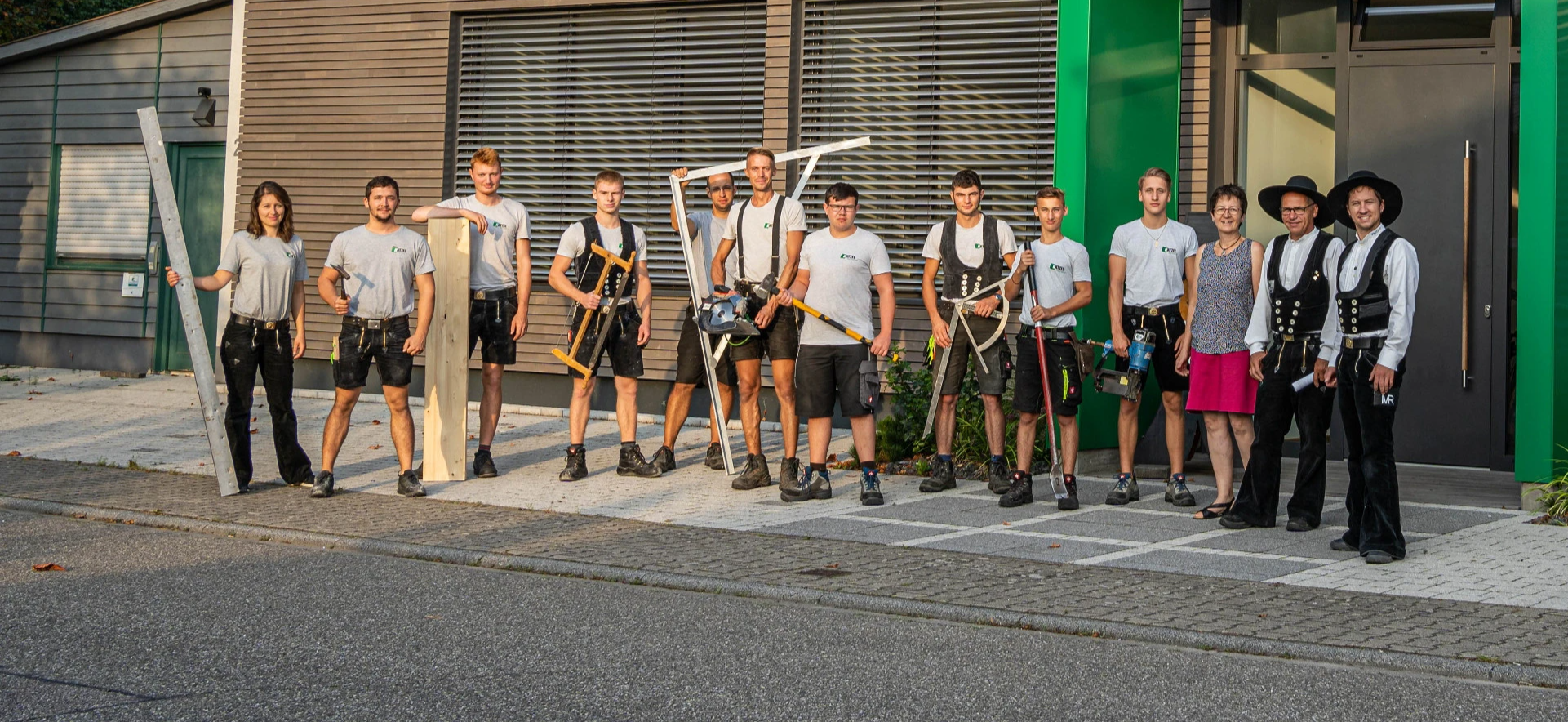 Gruppe von Menschen steht vor einem Gebäude, einige halten Werkzeuge und Instrumente.