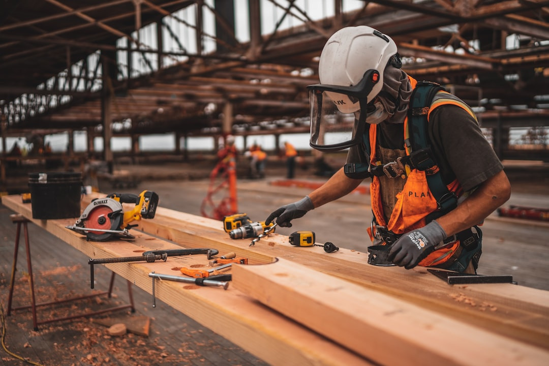 Ein Arbeiter in Schutzausrüstung bearbeitet Holz auf einer Baustelle.
