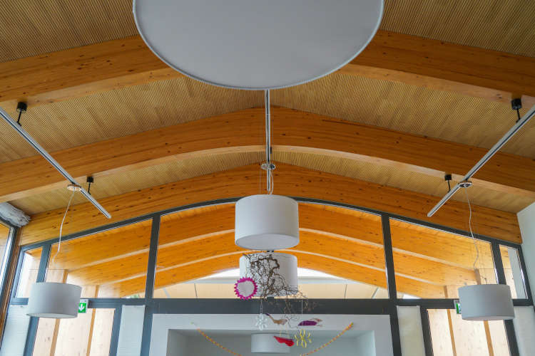 Ein modernes Innenraumdesign mit Holzbalken, runden Deckenlampen und großen Fenstern.